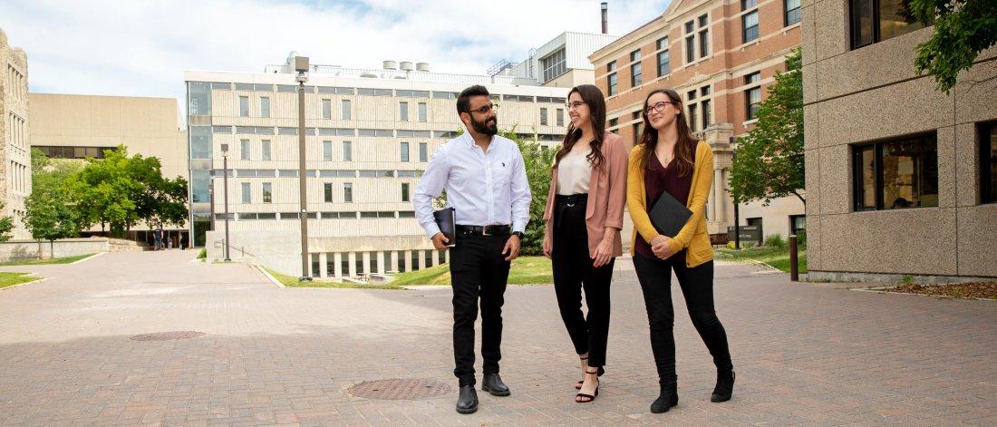 Three students walking outdoors together at the University of Manitoba Fort Garry campus.