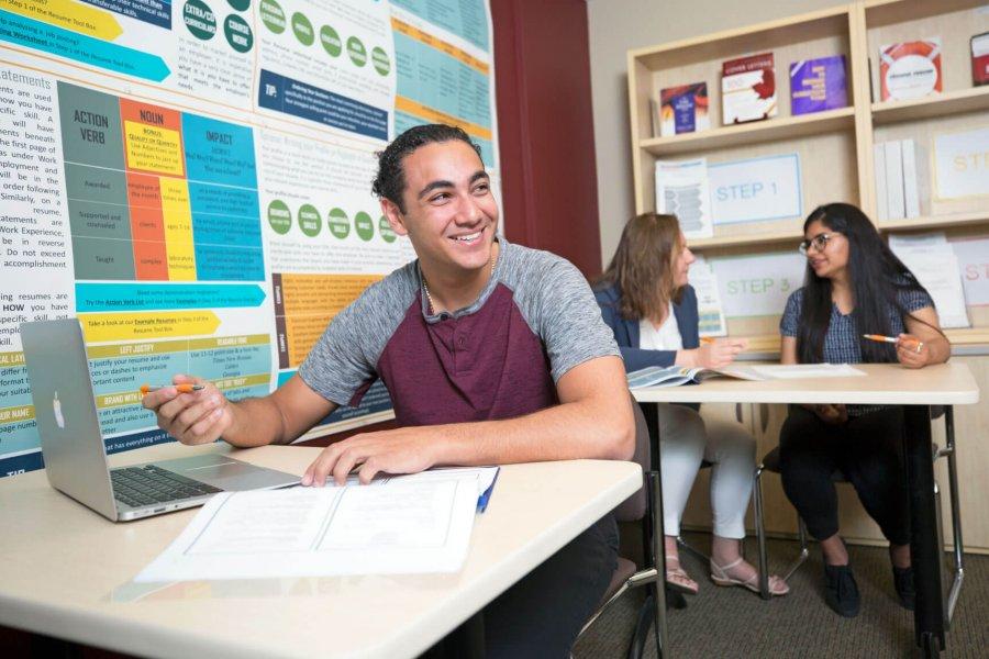 A student sits at a desk with a laptop at the Career Services office.