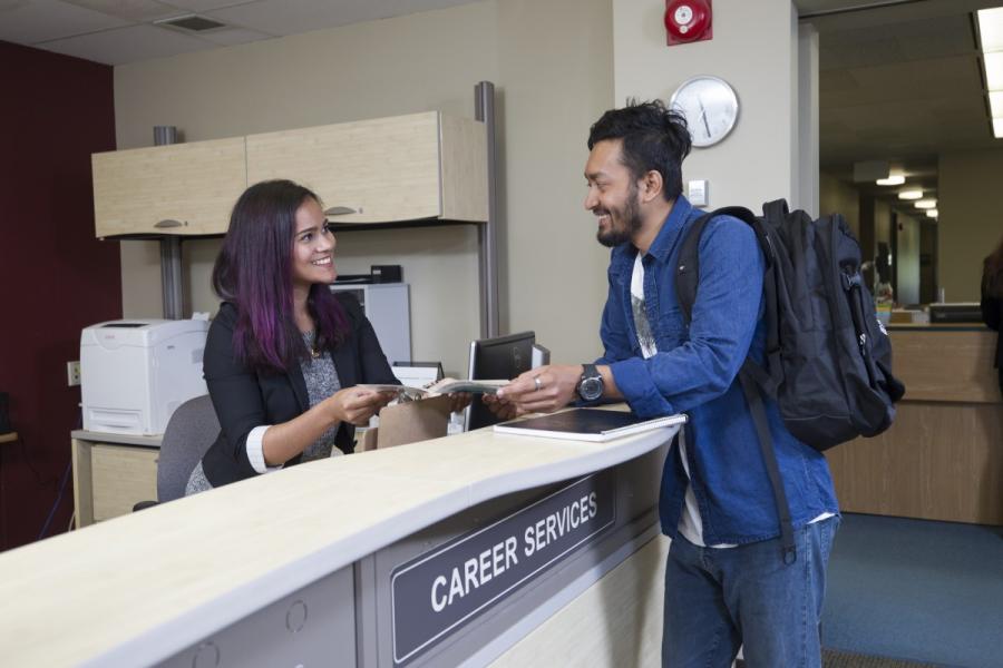 Photo of young woman helping a young man at reception desk