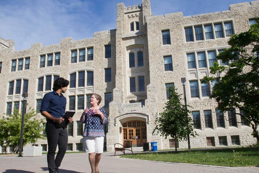 Mentor and student talking outdoors in campus