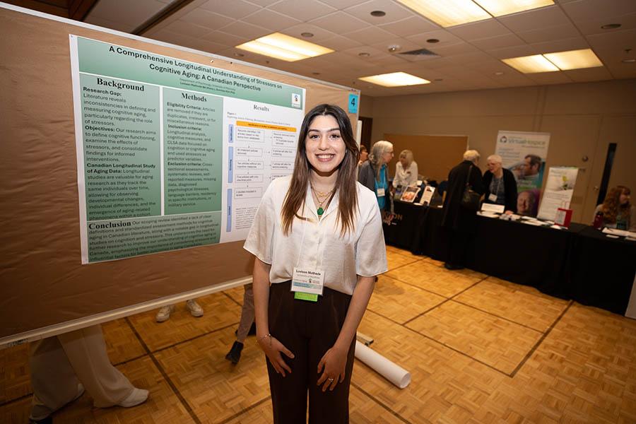 A students stands beside her poster presentation at the 41st Spring Research Symposium