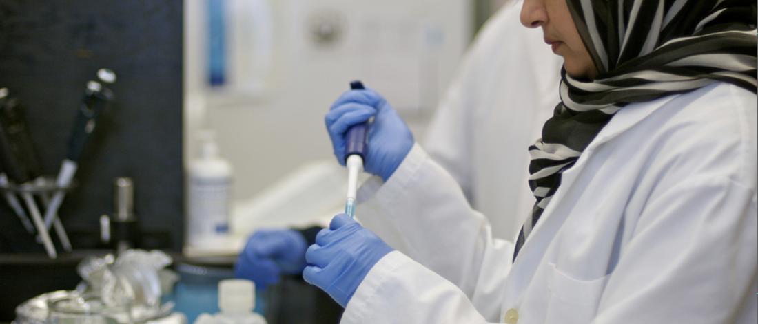 A researcher in a lab, using a pipette.