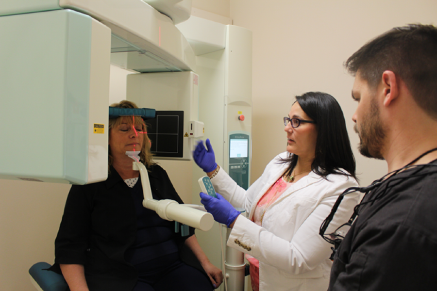 A facial imaging scan conducted on a patient as a dentists look on.