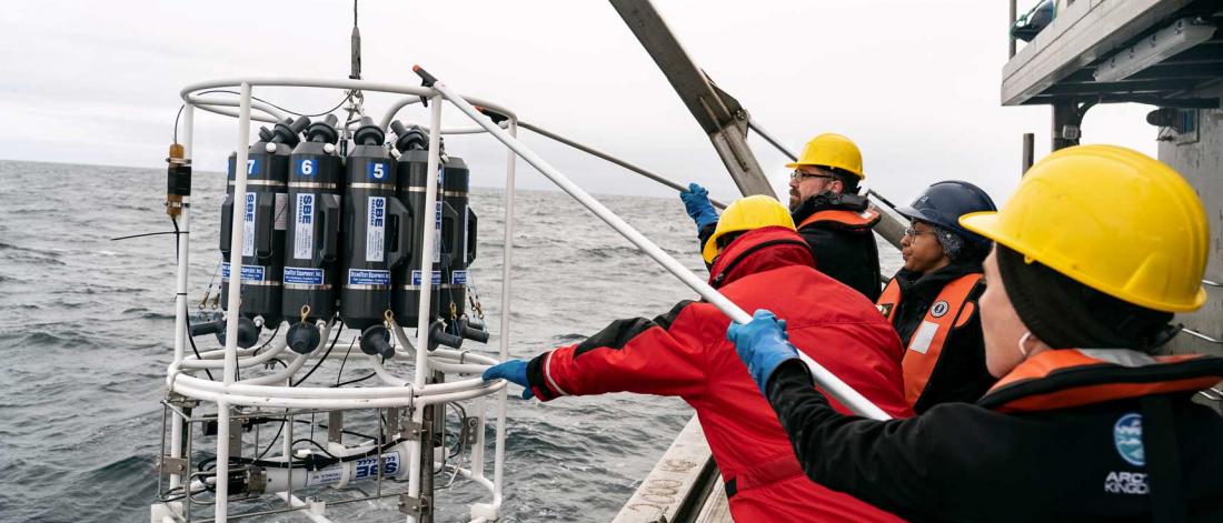 researchers lowering equipment into the water from the William Kennedy.