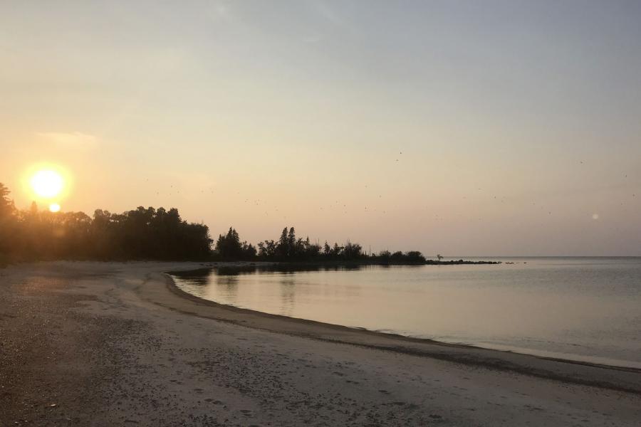 The sun setting over the trees on a beach on George Island.