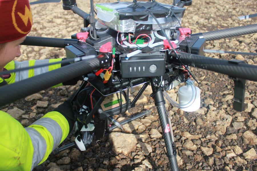 a researcher mounting a mercury sampler on a drone for aerial measurement at the site of the eruption.