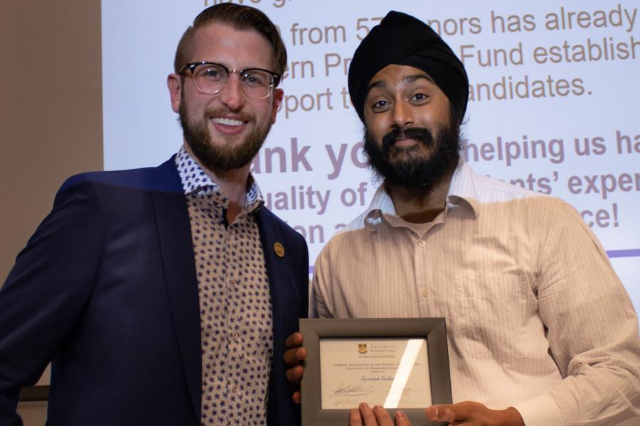 Gursevak Kasbia stands and holds the Education Alumni Association award he was presented with.
