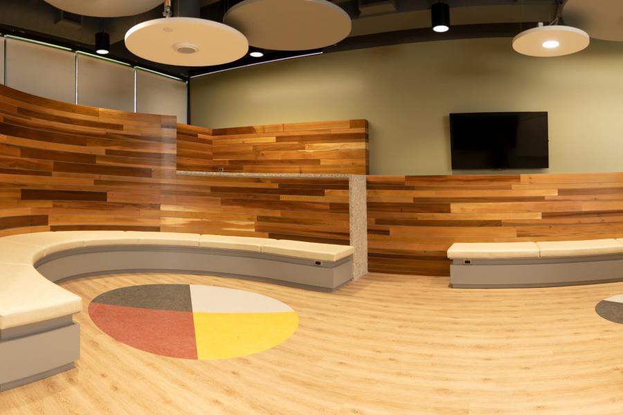 Interior view of the newly constructed Indigenous student community space with circular bench seating, and a medicine wheel built into the floor.