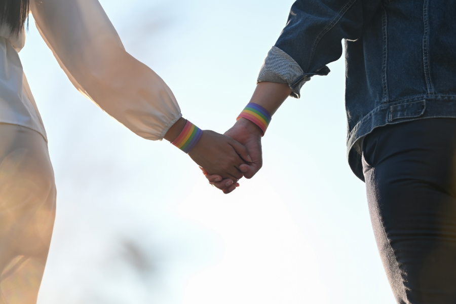 two people holding hands wearing rainbow bracelets