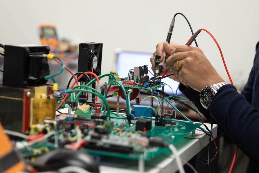 A pair of hands carefully work with electrical equipment.