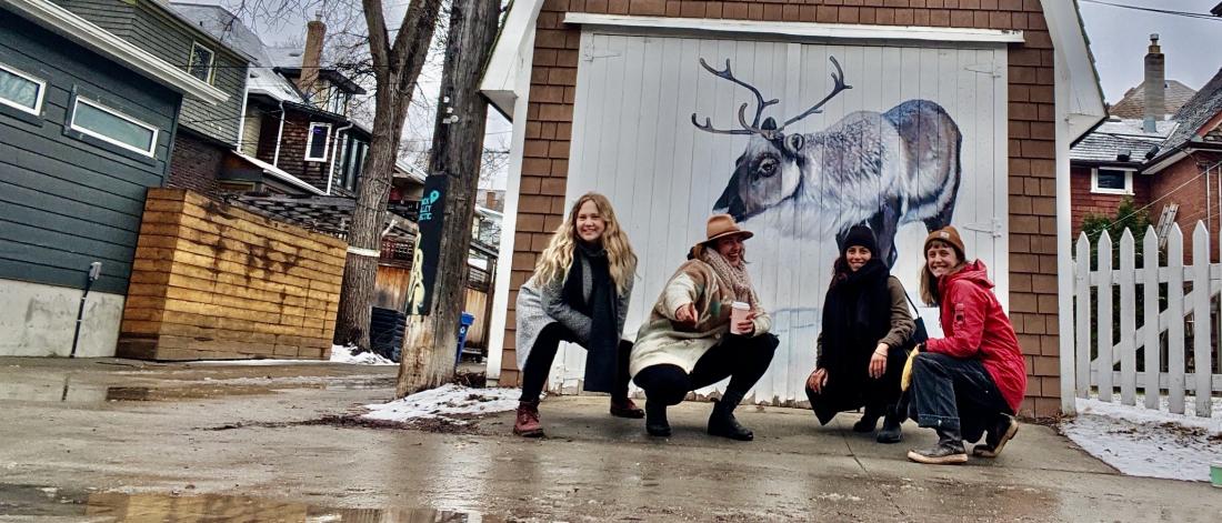 Grad students in front of a mural of a reindeer
