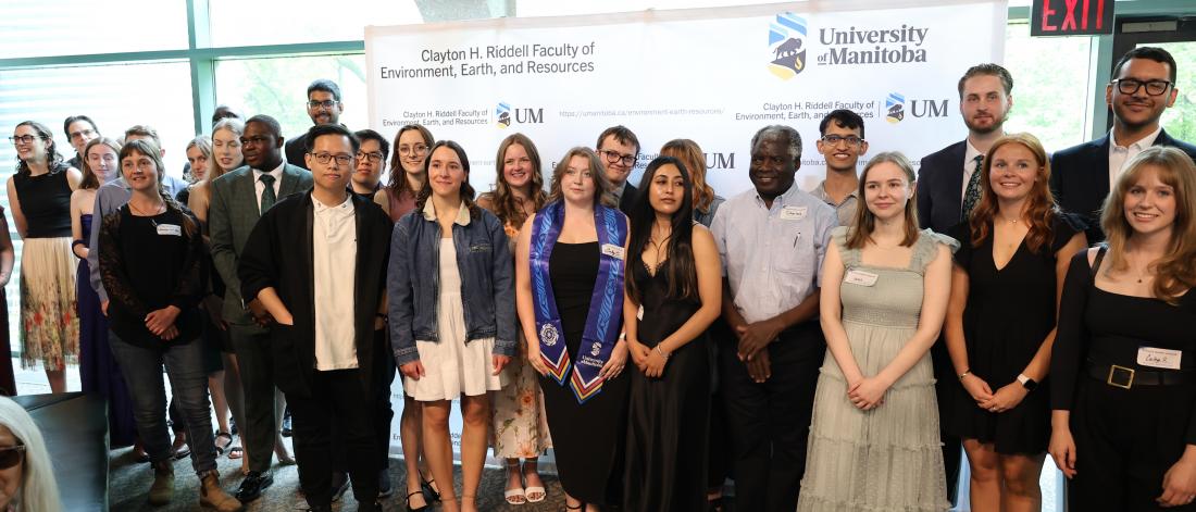 All graduating students in June Convocation pose for a photo in front of the Riddell Banner