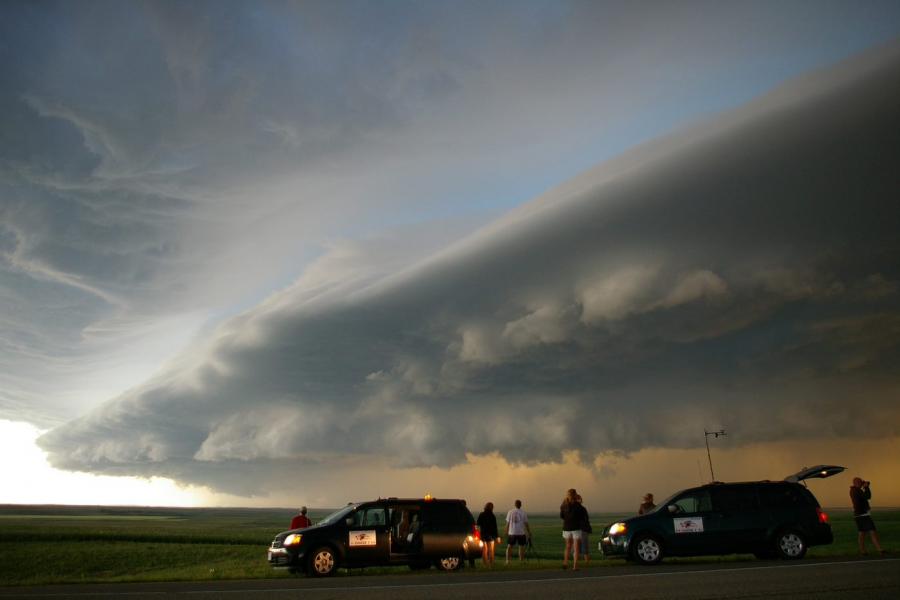 Storm chasers standing by their vehicles with ominous weather overhead.