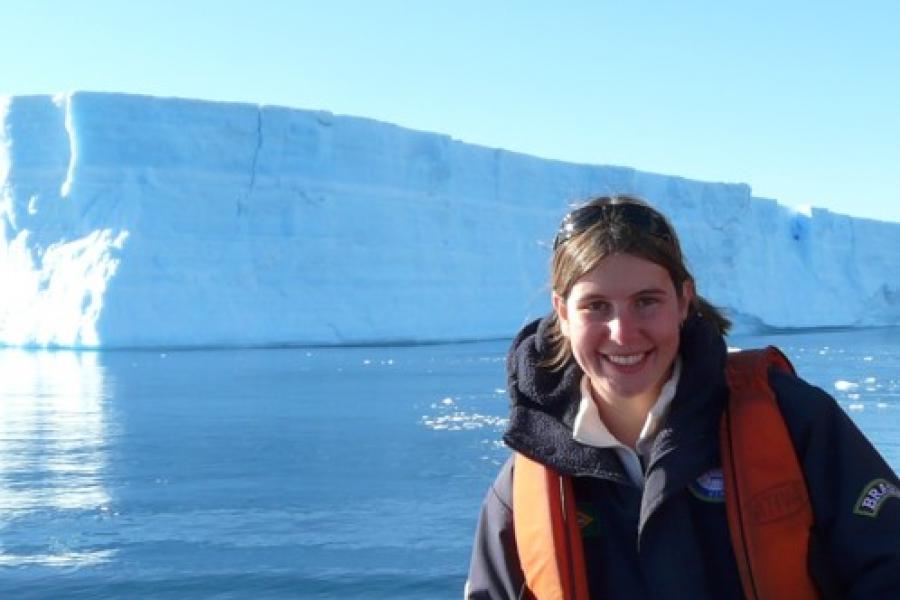 Dr. Juliana Marson on a boat posing in front of an iceberg.