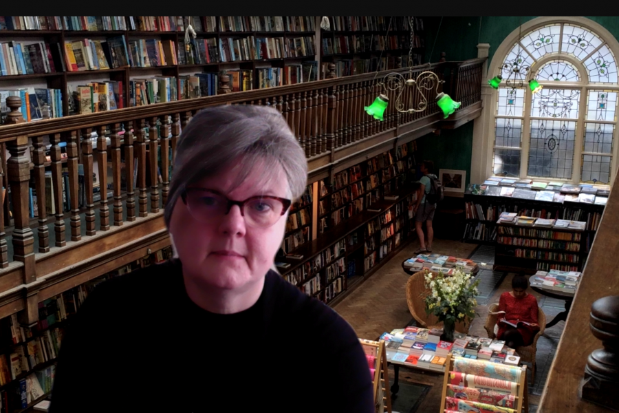 Dr. Bonnie Hallman standing inside a library with many books on the wall behind her.