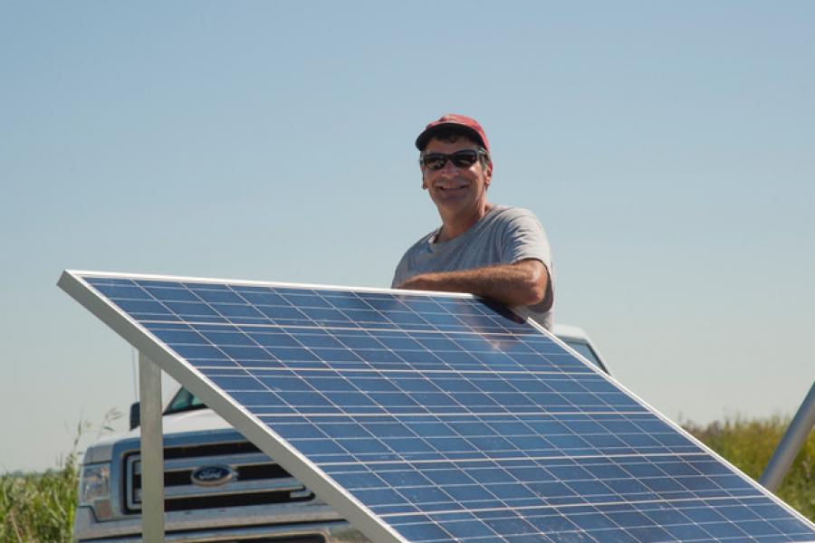 Doctor Tim Papakyriakou standing behind a solar panel.