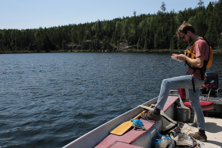 Tyler Black takes notes as from his boat on a lake