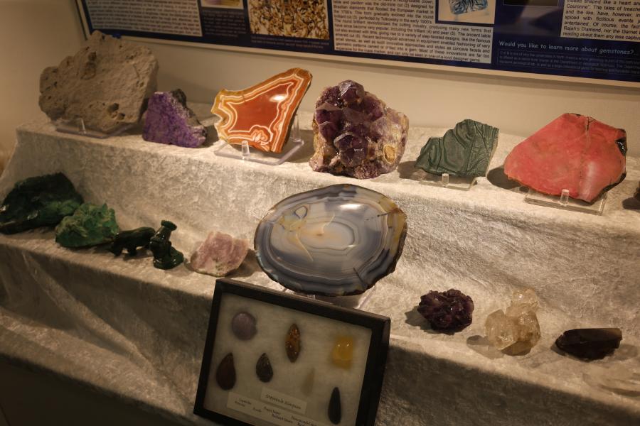 A variety of different rocks, crystals, and minerals on display behind glass.