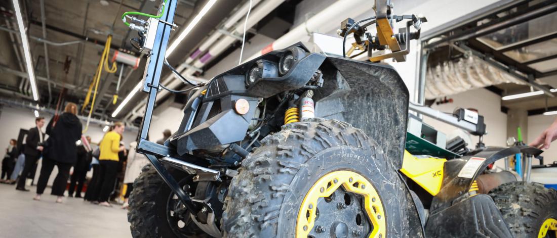 An all terrain vehicle student project with a small group of engineering students in the background.