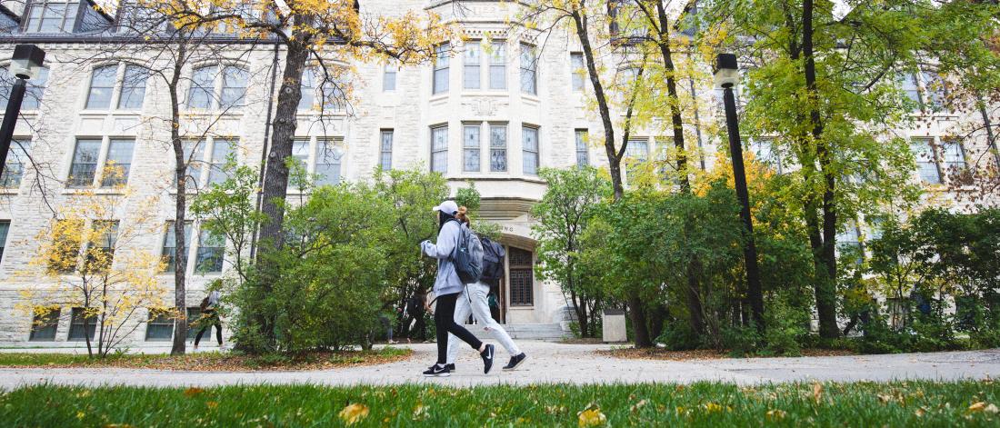 Two students walking outside, in front of the Tier building