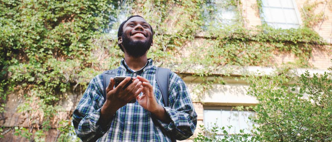 A smiling student holding a smart phone.