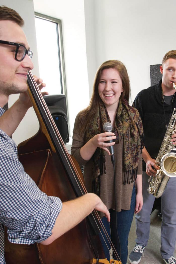 Three music students having a jam session with instruments in hand.