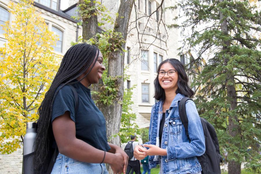 Two students stand together talking outside of the Tier building at the University of Manitoba Fort Garry campus. 