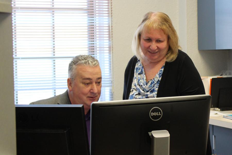 A social work student works at a computer with a supervisor. 