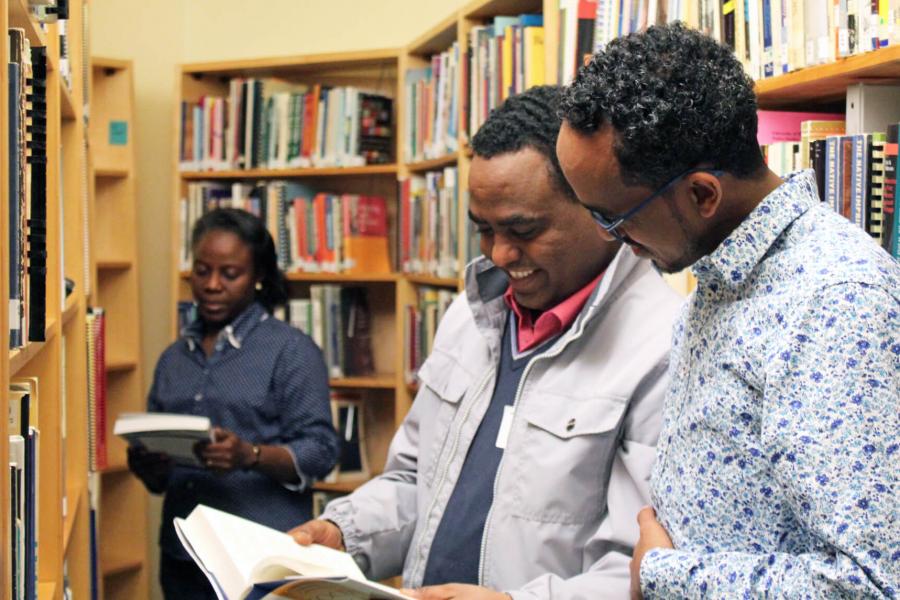 Three social work students look at books in the library.