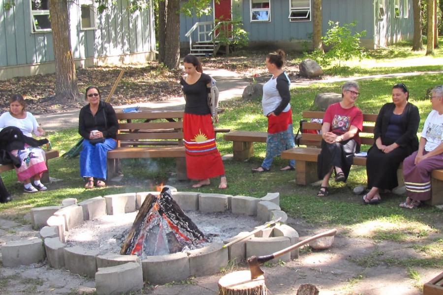 A group of social work student participants gather around a fire pit shaped like a turtle. 