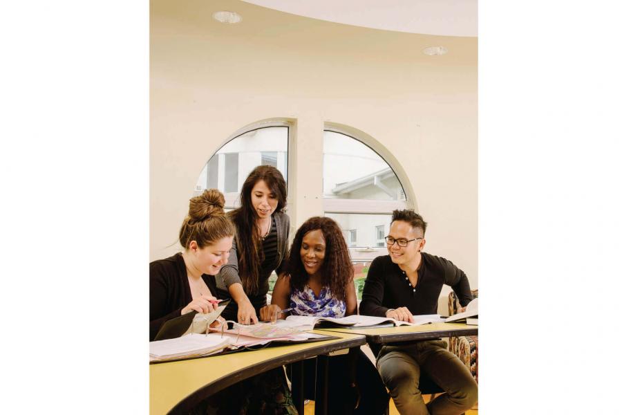 A group of studying social work students pointing out something specific in one of their notebooks.