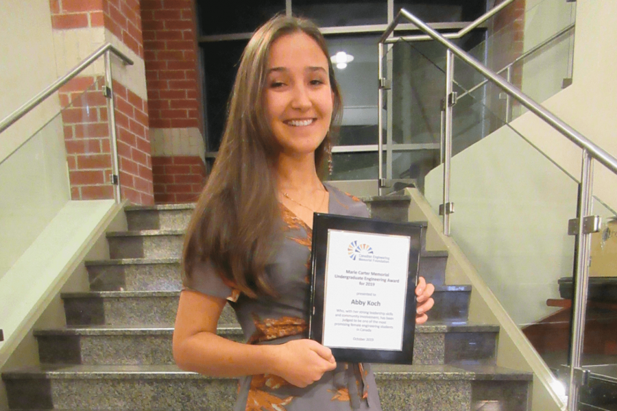 A biosystems engineering student holds an award she has received. 