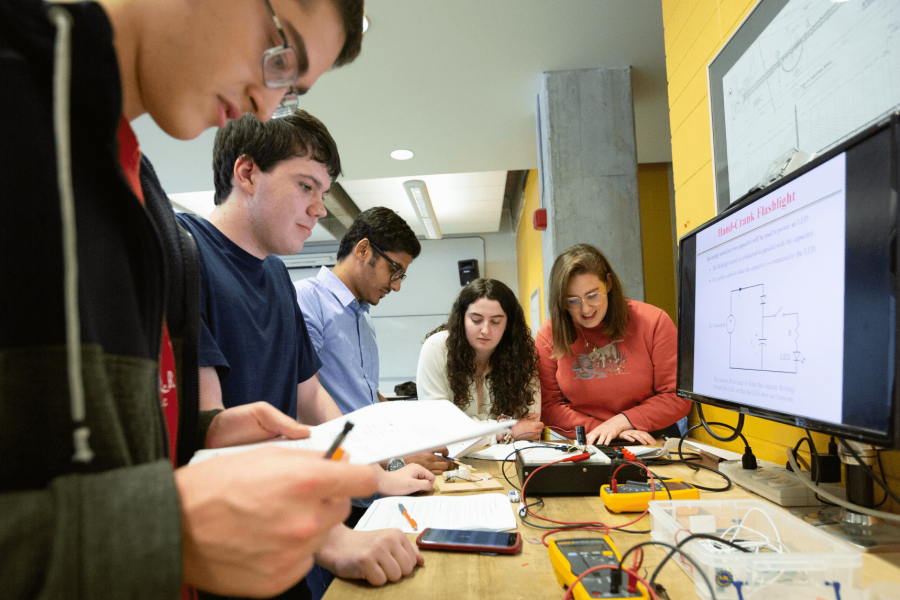 A group of engineering students works at a table together on a project.