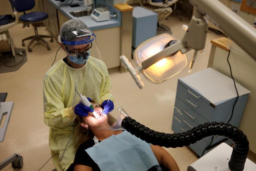 A dentists performs an oral exam on a patient.