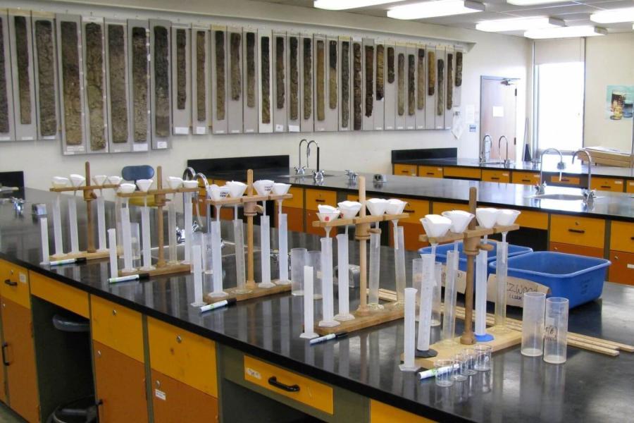 A soil science teaching lab with rows of test tubes on tables and soil samples on the wall.