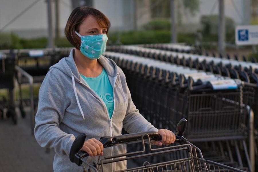 Woman wearing a mask pushes a shopping cart.