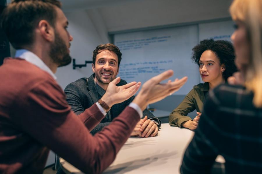 Group of four people in a discussion sitting around a table.