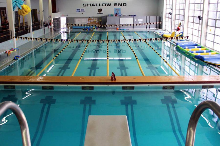 Large swimming pool from the perspective of a diving board. The main pool area is divided into six swimming lanes.