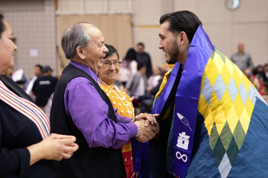 A student receives his Indigenous scarf at the graduation Pow Wow.