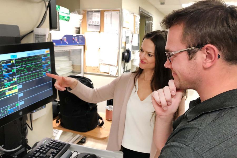 A female and male look at a computer monitor in a lab.