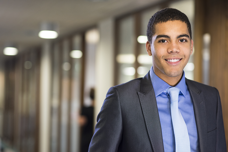 Young business professional standing in a hallway.