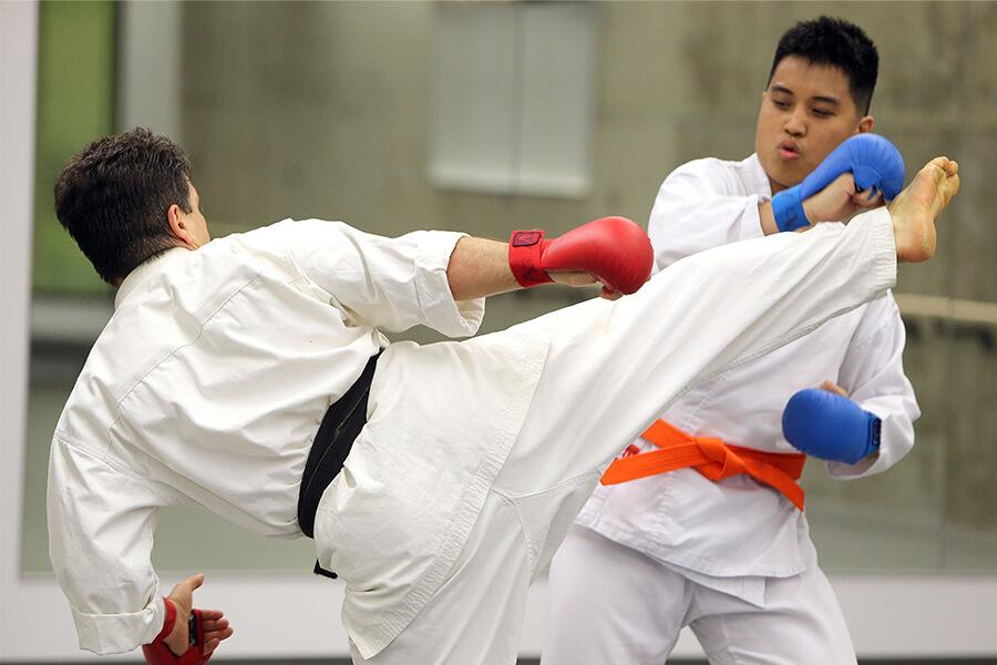 Two students practicing kick boxing in white uniforms.