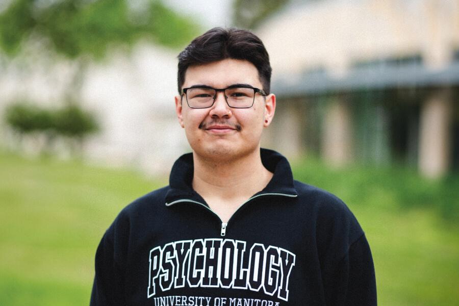 Image of a Indigenous student wearing a UM Psychology sweatshirt. 