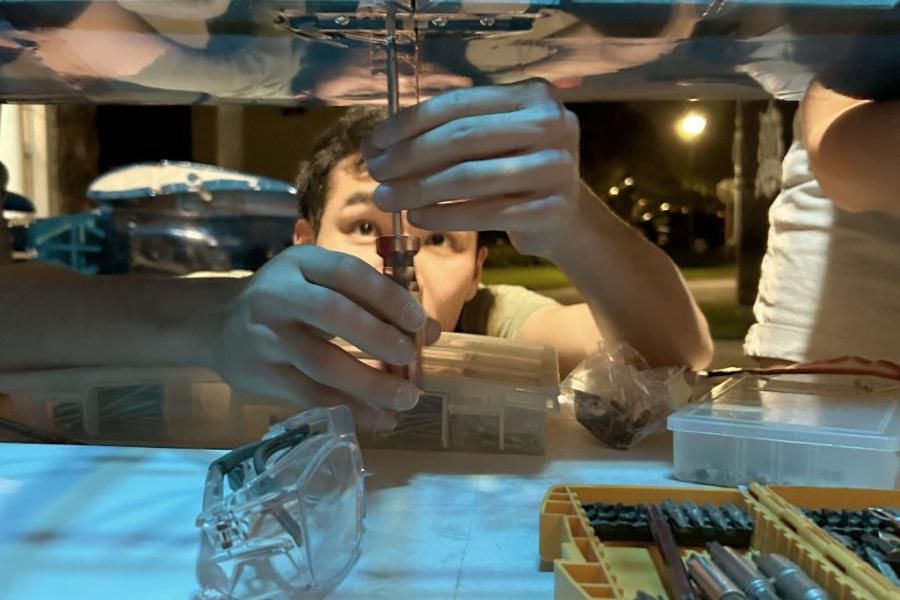 Student using tools to adjust something in a lab.