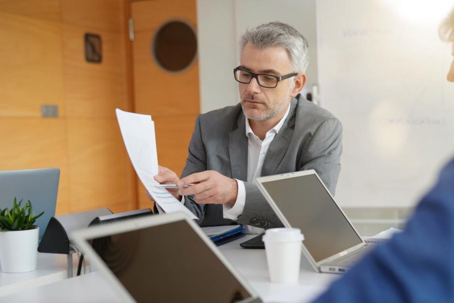 middle aged manager presents report to two colleagues