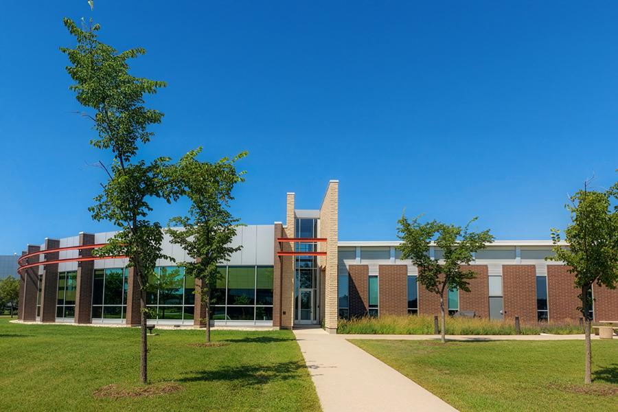 Large brown building with many windows and blue sky located at 135 Innovation Drive.
