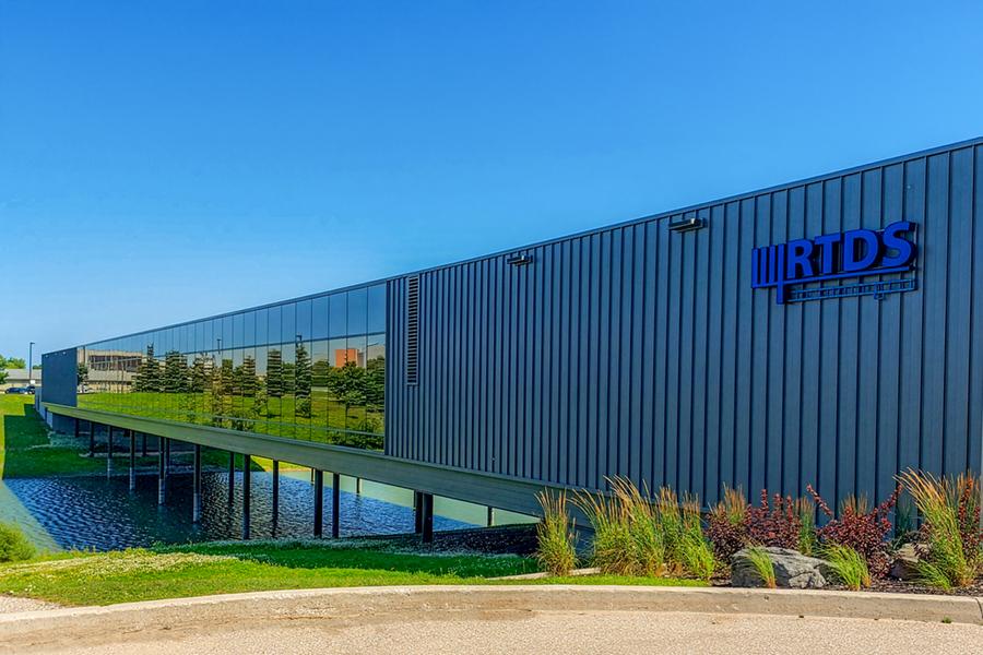 Large, long building with many windows spanning over a manmade lake at 150 Innovation Drive.