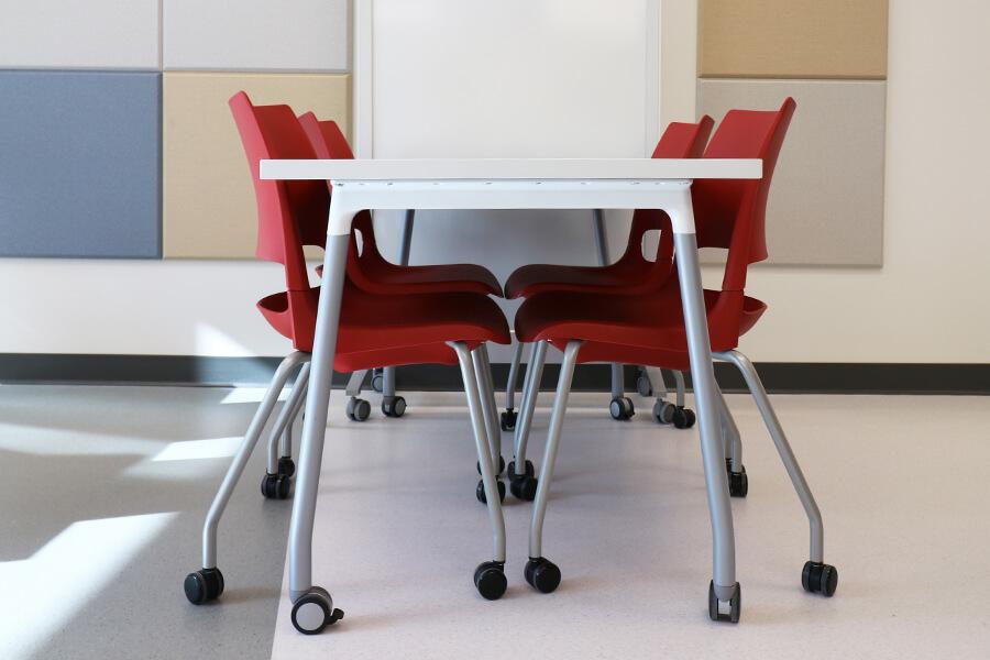 Red office chairs neatly tucked under a table.