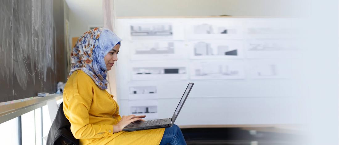 An architecture and city planning student carefully works on a project at her laptop.