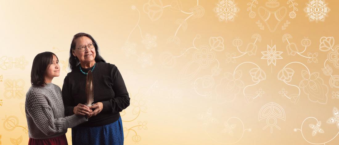 Elder Florence Painter and her granddaughter holding a feather and smiling.
